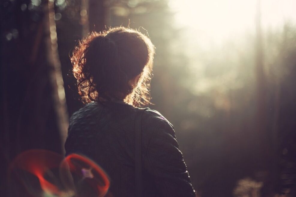 women in forest with trees & bright sun shinning