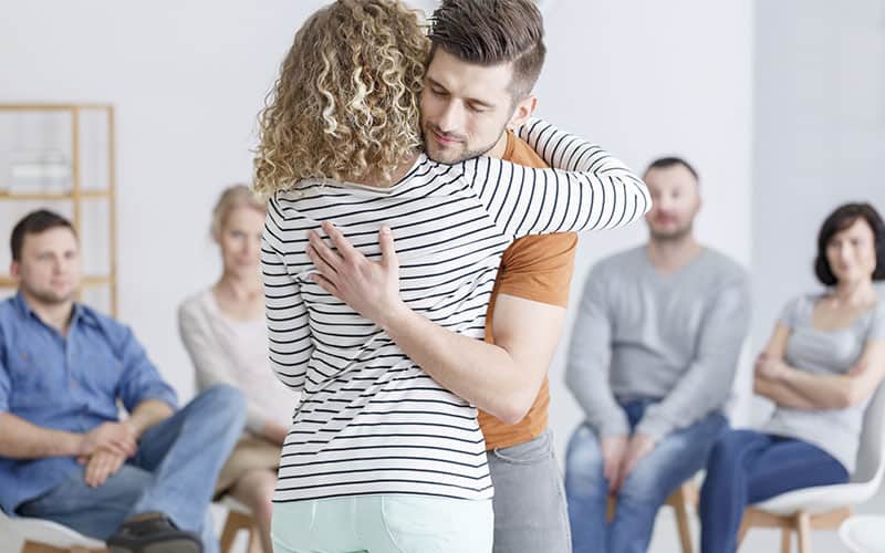 Group session with man and women hugging each other