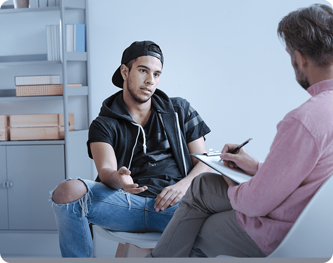 young man with ripped jeans & black cap with counselor