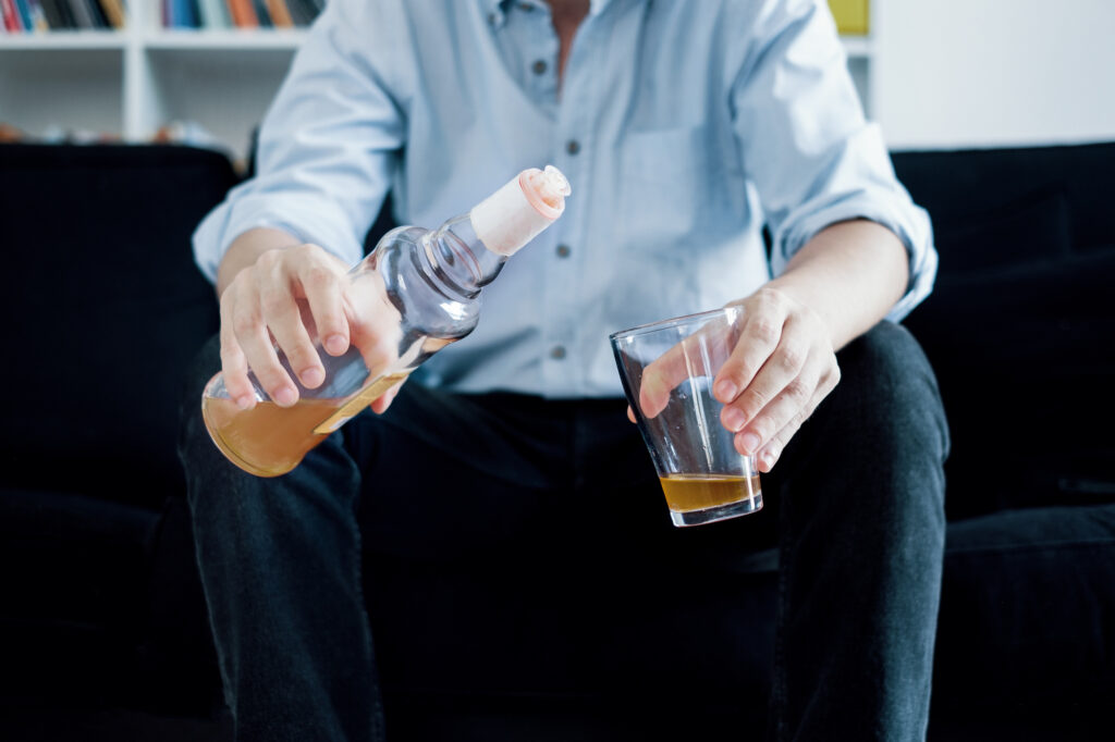 A man sitting pouring alcohol in a glass