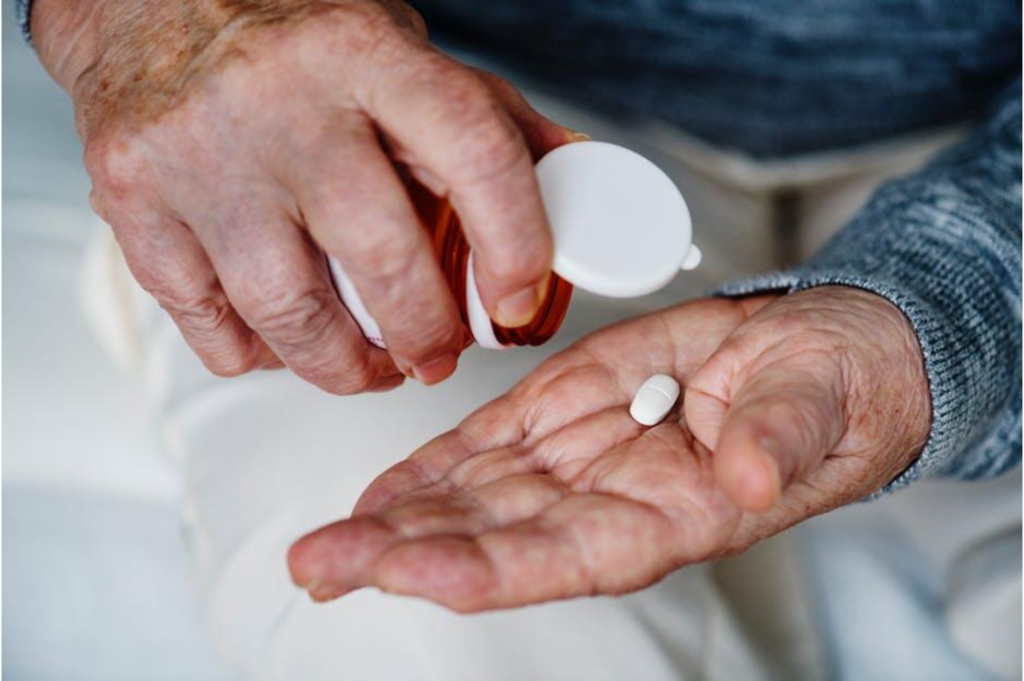 A man taking a pill out of a bottle into his hand